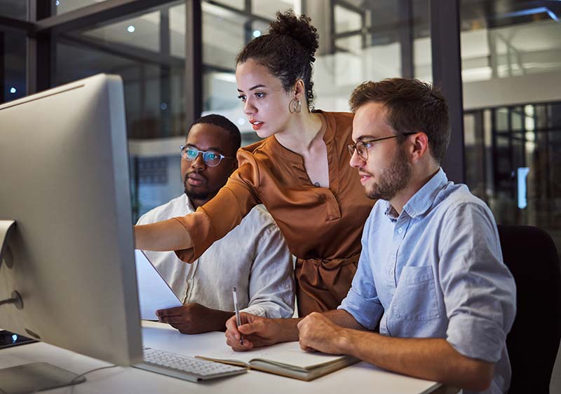 team of it professionals reviewing information on desktop screen
